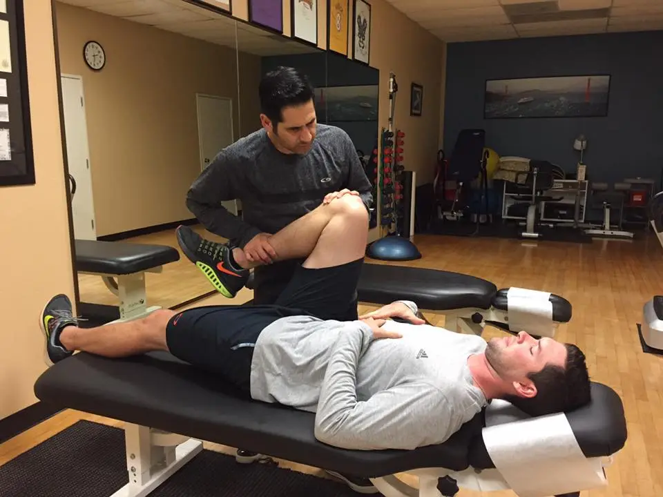 Chiropractor stretching a patient's leg during a sports injury exam