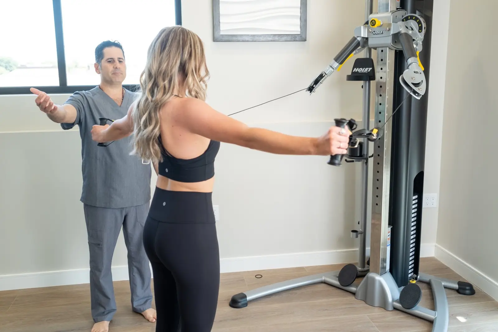 Chiropractor coaching a patient through cable rehab exercises